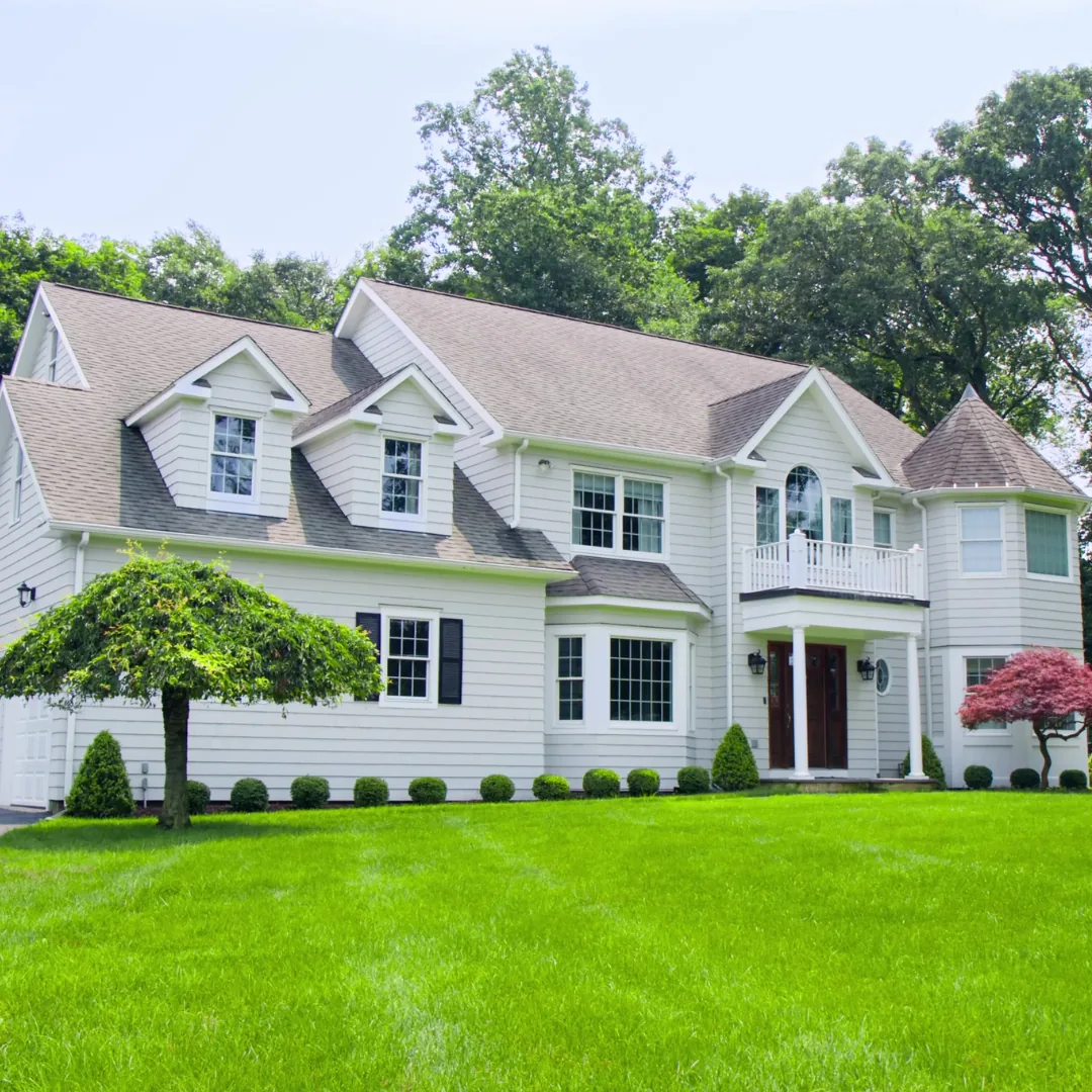 Freshly painted white colonial home with manicured lawn